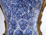 a blue and white vase sitting on a gold stand