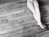 black and white photograph of a naked woman laying on a wooden floor