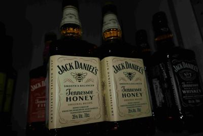Des bouteilles de Jack Daniel's Honey sont posées sur une étagère dans un bar
