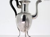 a silver tea pot with a black handle on a table