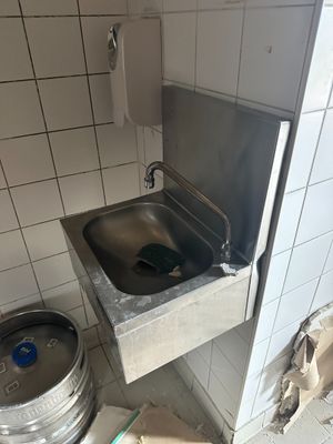 un lavabo dans un coin de la salle de bains, avec un seau d'eau