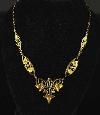 a gold necklace on a mannequin neck with a black background