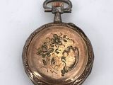 a gold pocket watch with a floral design on it
