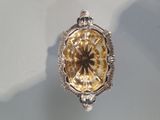 silver and gold pendant with a fancy design on a white surface