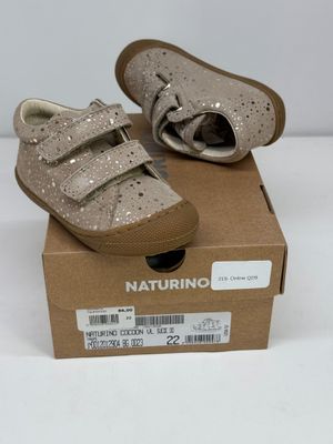des chaussures pour bébé dans une boîte posée sur une surface blanche, sur fond blanc