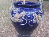 un vase bleu orné de deux oiseaux, posé dans l'herbe