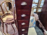 a tall wooden chest of drawers next to a wicker chair