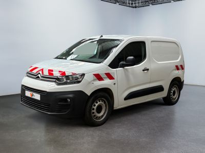 La camionnette blanche est garée dans une pièce blanche, avec une bande rouge et blanche sur le côté.