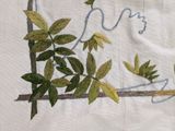 embroidery of a bird on a branch with leaves on a white cloth