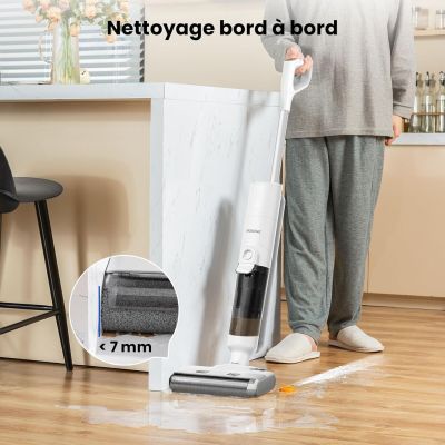 La femme nettoie le sol avec un aspirateur et un balai.