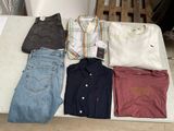 Plusieurs paires de chemises et de jeans pour hommes sont disposées sur une table