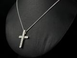 a silver cross necklace on a mannequin neck with a black background