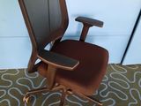 une chaise de bureau marron avec une assise marron, posée sur un tapis