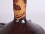 a brown vase with leaves on it sitting on a table
