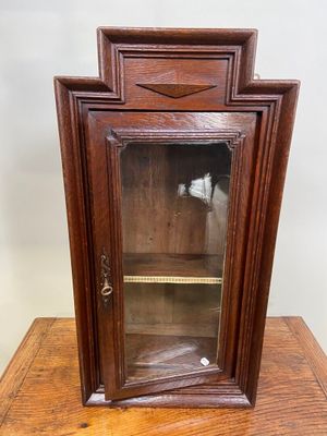 une vieille armoire en bois avec une porte vitrée, posée sur une table en bois