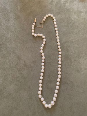 un collier de perles blanches avec un fermoir en or