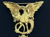 un gros plan d'une broche en or ornée d'un aigle