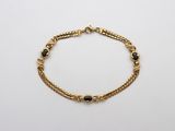 un bracelet en or orné de pierres noires sur fond blanc
