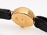 a gold watch with a black leather band on a white surface