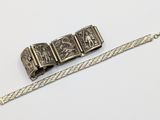 an antique silver bracelet and a silver bracelet on a white surface