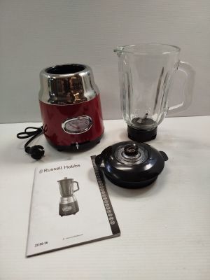 a red blender sitting on a table next to a book