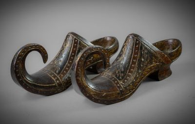 pair of wooden shoes with carved designs on them on a gray surface