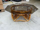 une table avec un plateau en verre et un piètement en osier