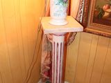 a lamp that is sitting on a pedestal in the corner of a room