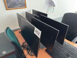 three computer monitors on a desk with a keyboard and mouse