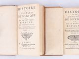 three old books sitting on top of each other on a white surface