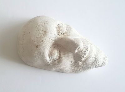 une sculpture blanche représentant le visage d'un homme sur une surface blanche