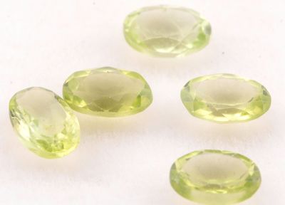 quatre pierres précieuses vertes sont disposées sur une surface blanche