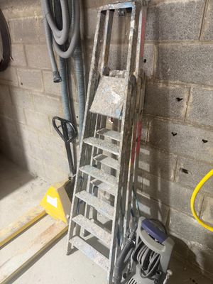 une échelle appuyée contre un mur, à côté d'un tas d'outils