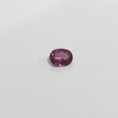 a pink sapphire stone on a white surface
