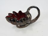 a silver and red bowl with a leaf on it