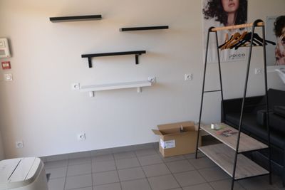 a room with a black couch and a shelf with clothes on it