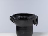 une image représentant un vase noir posé sur une table blanche