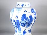 a blue and white vase with a picture of people sitting at a table