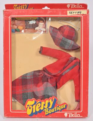 poupée dans une boîte rouge, vêtue d'une robe à carreaux et d'un chapeau assorti
