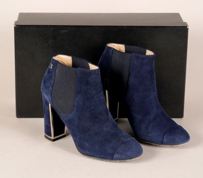 une paire de bottines en daim bleu devant une boîte noire