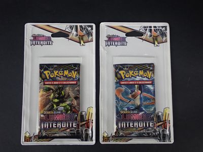 On voit deux paquets de cartes à collectionner Pokémon posés sur une surface noire.