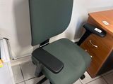 a green office chair sitting in front of a wooden desk