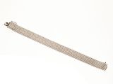 gros plan d'un bracelet métallique sur une surface blanche