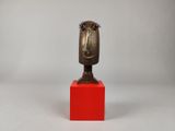 sculpture représentant une tête posée sur un socle rouge