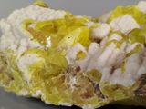 a piece of rock with yellow and white crystals on it