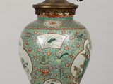 a large vase on a table with a lamp on it