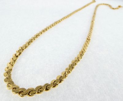 a close up of a gold chain necklace on a white surface