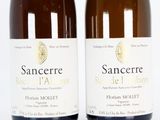two bottles of wine sitting next to each other on a white surface