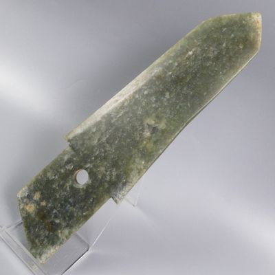 couteau en pierre verte posé sur un socle en acrylique transparent, sur fond blanc