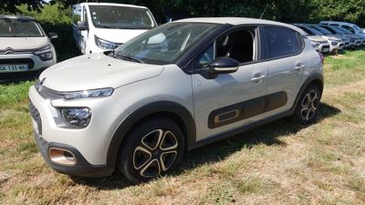 une voiture argentée garée dans un champ, avec d'autres voitures en arrière-plan